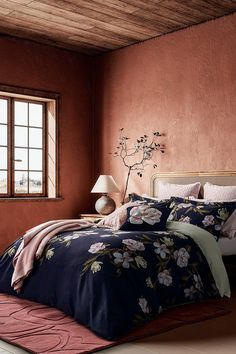 a bed in a room with red walls and a flowered comforter on it