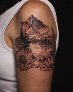 a woman with a tattoo on her arm that has flowers and mountains in the background