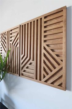 a plant is sitting on the wall next to a wooden paneled piece with geometric designs