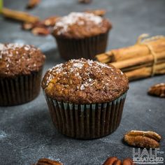 three muffins with powdered sugar on top and pecans scattered around them