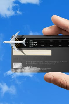 a person holding up a business card with an airplane flying in the sky behind it