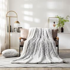 a living room with a couch and chair covered in a white blanket next to a potted plant