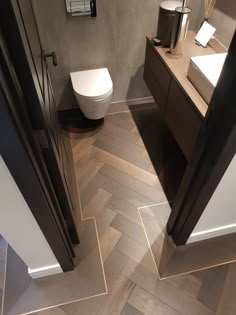 a bathroom with wood flooring and white toilet next to a sink in the corner