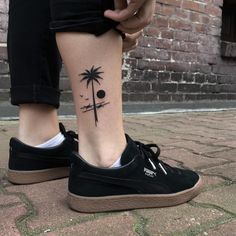 a person with a palm tree tattoo on their leg, standing in front of a brick wall