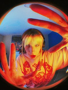 a woman is holding her hands up in front of the camera with red light coming from it