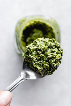 a hand holding a spoon full of pesto