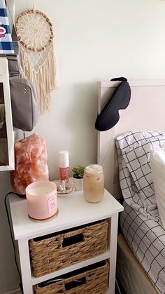 a white table with baskets and items on it next to a bed in a bedroom