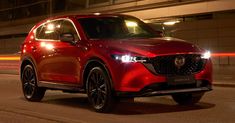 a red suv driving down the street at night