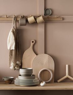 a shelf with plates, bowls and cups on it next to a wooden rack holding kitchen utensils