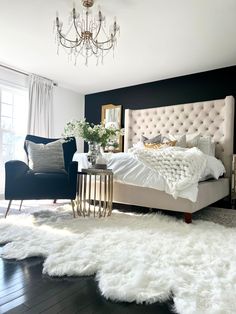 a bedroom with black walls, white fur rugs and a chandelier hanging from the ceiling