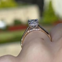 a close up of a person's hand holding a ring with a diamond on it