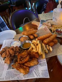 fried chicken, french fries and dipping sauces are on the table at a restaurant