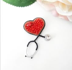 a red beaded heart with a stethoscope attached to it on a white surface