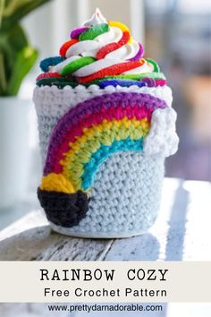 a crocheted cupcake with rainbow frosting on top, sitting on a table