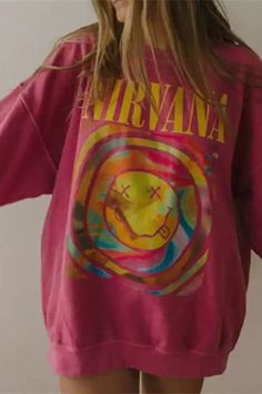 a woman wearing a pink nirvana sweatshirt with the words nirvana on it