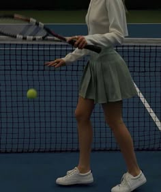 a woman in white shirt and green skirt holding a tennis racquet on a court