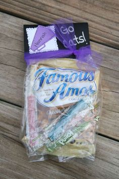 an assortment of candy wrapped in plastic on top of a wooden table next to a purple ribbon