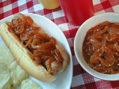 two white plates with chili cheese dogs and chips on a red checkered tablecloth