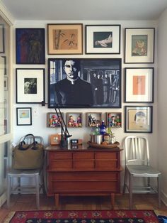 a living room with pictures on the wall and a dresser in front of it,