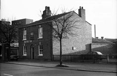 black and white photograph of an old brick building on the corner of a city street