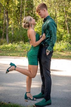 a man standing next to a woman in a green dress