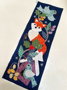 a blue table runner with an image of a fox and bird on it's side