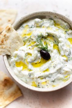 a white bowl filled with dip and pita chips