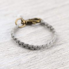 a braided bracelet with an antique brass clasp on a white wooden surface, close up