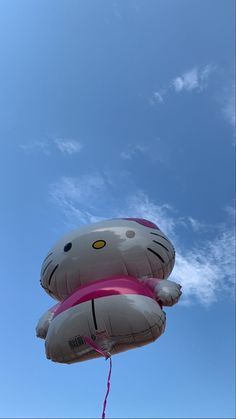 an inflatable hello kitty balloon is flying through the air with a blue sky behind it