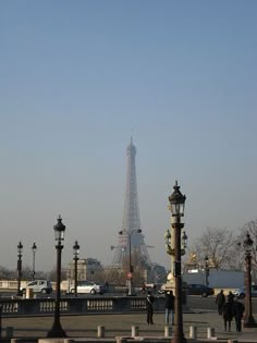 the eiffel tower is in the distance with people walking on the sidewalk below