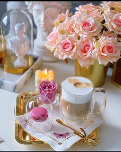 a tray with pink roses and two mugs on it, next to a candle