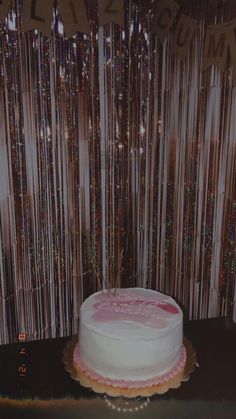 a white cake sitting on top of a table next to a wall covered in sequins