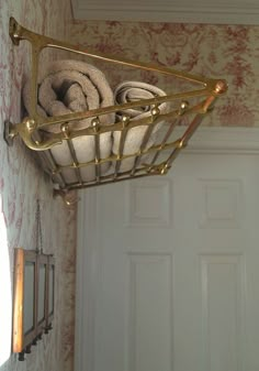 two towels are in a basket hanging on the wall next to a door with gold handles