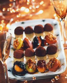 an assortment of desserts on a white plate next to wine glasses and champagne flutes