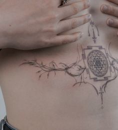 a woman's stomach with an intricate design on the side and her hands holding it