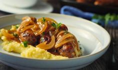 a white bowl filled with meat and onions on top of mashed potatoes in gravy