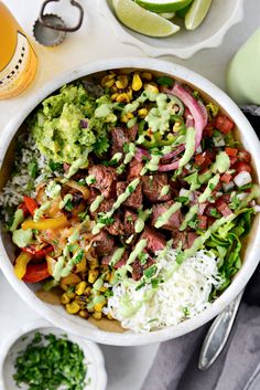 a bowl filled with meat, rice and veggies on top of a table