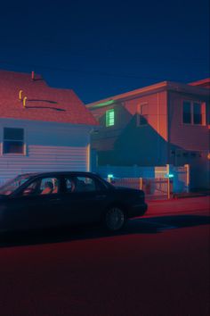 a car is parked on the street in front of some houses at night with red lights