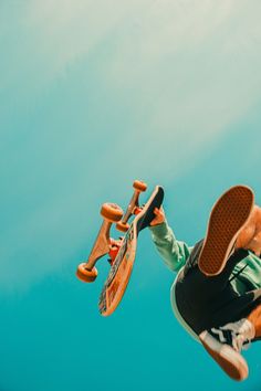 a man flying through the air while riding a skateboard in front of a blue sky