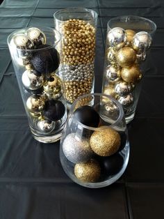 several glass vases filled with ornaments on top of a black tablecloth covered table