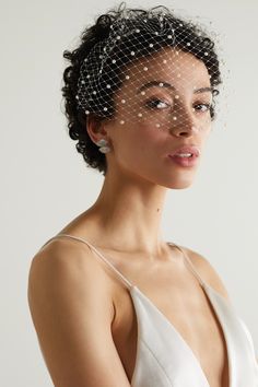 a woman in a white dress wearing a birdcage veil with pearls on it