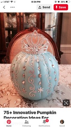 a blue pumpkin with a tiara on top sitting on a table in front of a china cabinet