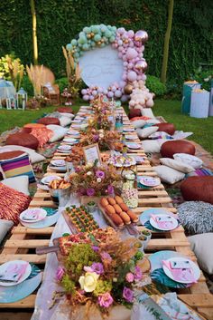 an outdoor table set up for a party with lots of food and decorations on it