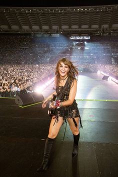 a woman standing on top of a stage in front of a crowd at a concert