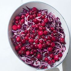 a bowl filled with red onions and cranberries on top of a white table