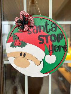 a santa stop here sign hanging on a door