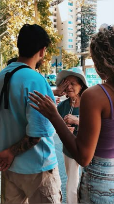 an old woman holding her head while standing next to two other people on the street