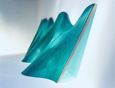 an abstract sculpture is shown against a white background with blue and green waves in the foreground