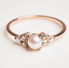 a pearl and diamond ring on a white surface