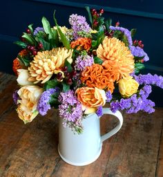 a white mug filled with lots of colorful flowers